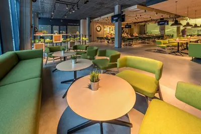 a restaurant with green and yellow chairs and tables at Urbihop Hotel in Vilnius