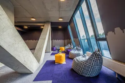 a room with three couches in a building with windows at Urbihop Hotel in Vilnius