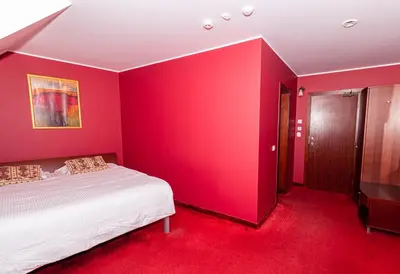 a bedroom with red walls and a white bed in it at Hotel Medūna in Druskininkai