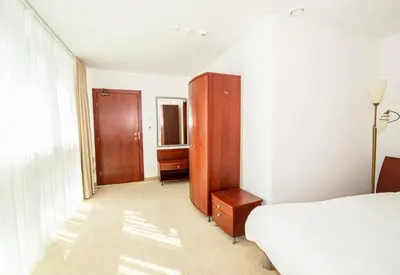 a bedroom with a bed and a wooden cabinet at Hotel Medūna in Druskininkai