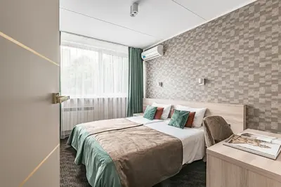a bedroom with a bed and a desk and a window at Hotel Zemaites in Vilnius