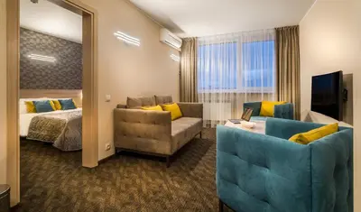 a hotel room with a bed and a couch and a mirror at Hotel Zemaites in Vilnius