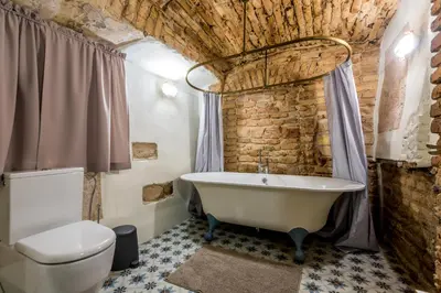 a bathroom with a white tub and a brick wall at Angel House Vilnius 29 in Vilnius