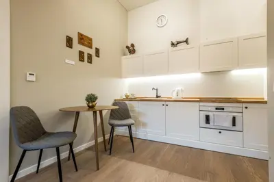 a kitchen with white cabinets and a table and chairs at Angel House Vilnius 38 in Vilnius