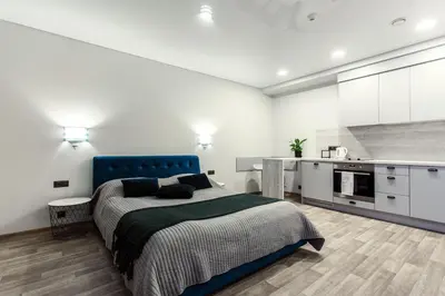 a bedroom with a blue bed and a kitchen at Old Town Trio Apartments in Vilnius