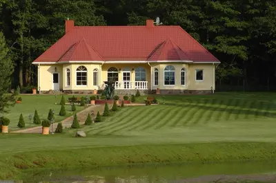 a large white house with a red roof at Gazdų Vandens Malūnas in Navininkai