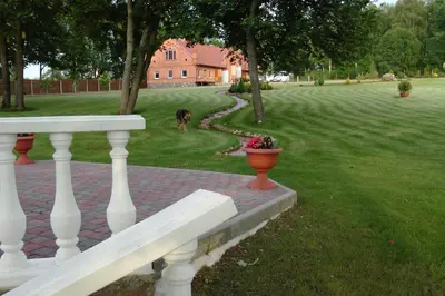 a white fence with a bench and a dog in a yard at Gazdų Vandens Malūnas in Navininkai