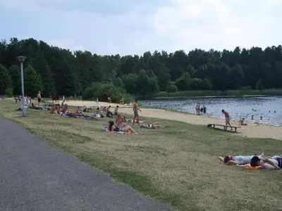 a group of people laying on the grass at a beach at Love Island Guesthouse in Druskininkai