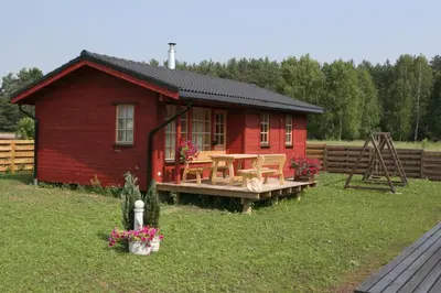 a red cabin with a table in the yard at Love Island Guesthouse in Druskininkai