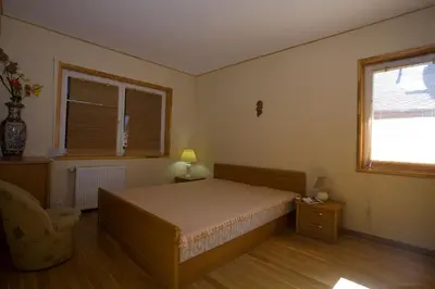 a bedroom with a bed and a chair and a window at Love Island Guesthouse in Druskininkai