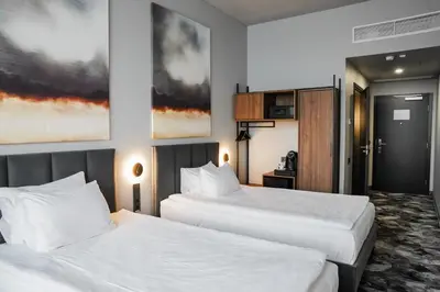 two beds in a hotel room with white sheets at Loop Hotel Vilnius in Vilnius