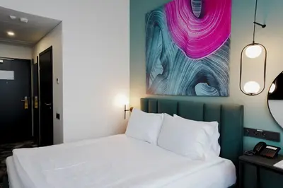 a bedroom with a bed and a painting on the wall at Loop Hotel Vilnius in Vilnius