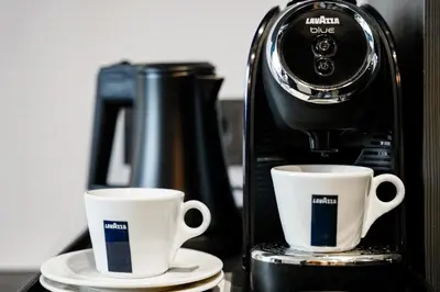 two coffee cups on plates next to a coffee maker at Loop Hotel Vilnius in Vilnius