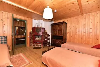 a bedroom with two beds and a wooden wall at Sodyba Sauletekis in Ignalina