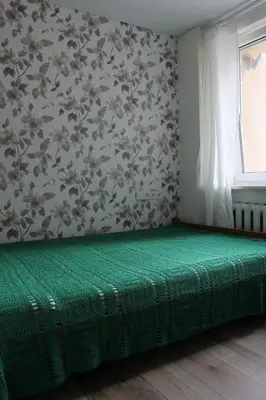 a green bed in a room with a wall at Near Park Apartment in Druskininkai