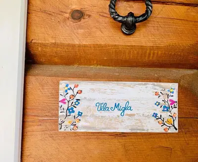 a wooden door with a sign that says who might at Vila Migla in Pašekščiai