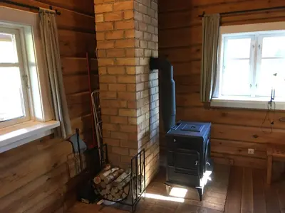 a wood stove in a room with two windows at Vila Migla in Pašekščiai