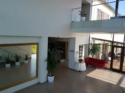 a lobby of a building with a red couch and potted plants at Rezidencija Grįžulo ratai in Sasnava