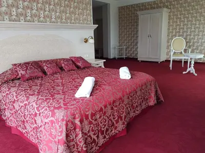 a bedroom with a red bed with two white towels on it at Rezidencija Grįžulo ratai in Sasnava