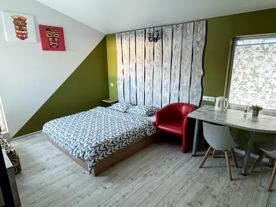 a bedroom with a bed and a table with a red chair at Lampedziai Apartment in Kaunas