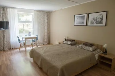 a bedroom with a bed and a table and a window at KAUNO JACHTKLUBAS Baltosios Burės in Kaunas