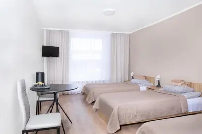 a hotel room with two beds and a table and a tv at KAUNO JACHTKLUBAS Baltosios Burės in Kaunas