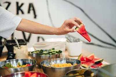 a person holding a piece of watermelon over a table of food at Corner Hotel in Vilnius