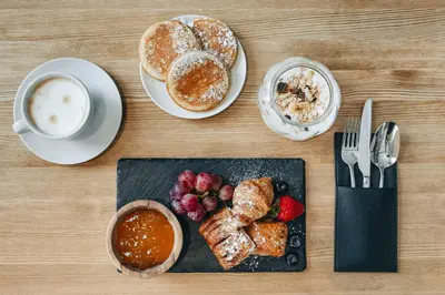 a table with a plate of pastries and a cup of coffee at Corner Hotel in Vilnius