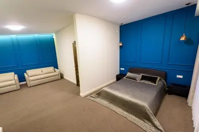 a bedroom with blue walls and a bed and a chair at Villa Orchidea in Šakiai
