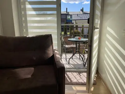 a couch sitting on a balcony with a table at Ados apartamentai in Druskininkai