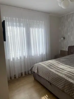 a bedroom with a bed and white drapes at Ados apartamentai in Druskininkai