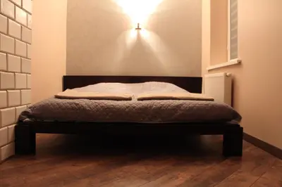 a bed in a room with a light on the wall at Apartamentai Kauno centre in Kaunas