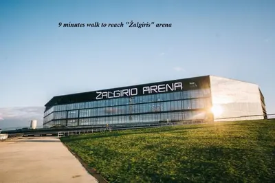 a large glass building with the sun shining on it at Apartamentai Kauno centre in Kaunas
