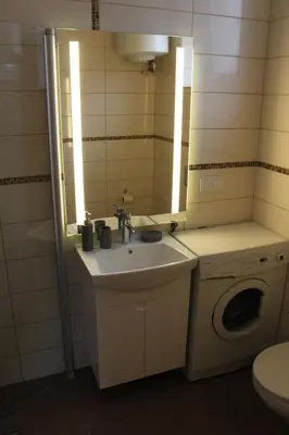 a bathroom with a sink and a washing machine at Apartamentai Kauno centre in Kaunas
