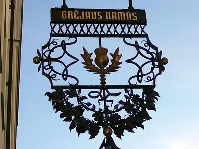 a wrought iron street sign on the side of a building at Grėjaus Namas in Kėdainiai