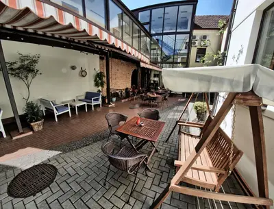 an outdoor patio with tables and chairs and a building at Grėjaus Namas in Kėdainiai