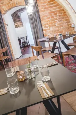 a dining room with tables and chairs and a brick wall at Grėjaus Namas in Kėdainiai