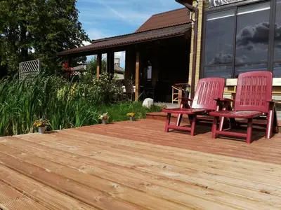 two red chairs sitting on a wooden deck at Raudonkalnis in Mankiškiai