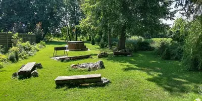 a park with benches in the grass with trees at Raudonkalnis in Mankiškiai