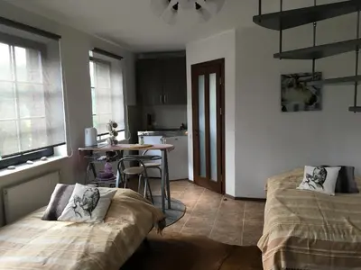 a room with two beds and a table and a kitchen at Villa Traku Terasa in Trakai