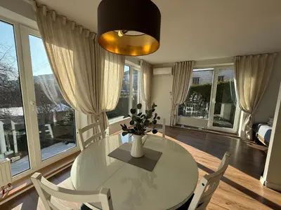 a dining room with a table and chairs and windows at Felix Apartment Free parking in Vilnius