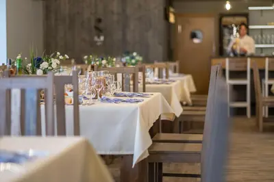 a row of tables in a restaurant with white table cloth at Žvejų užeiga in Šiauliai