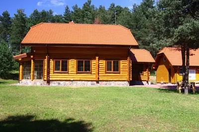a wooden cabin in a field with a grass yard at Asvejos slenis in Sužionys