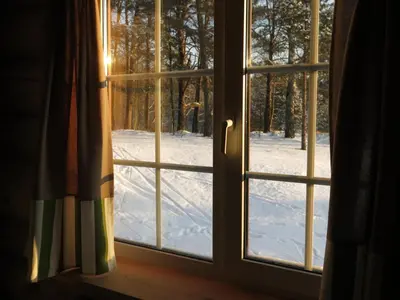 a window with a view of a snow covered yard at Asvejos slenis in Sužionys