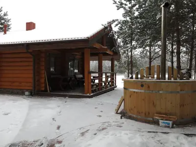 a cabin in the snow with a table and a barrel at Asvejos slenis in Sužionys