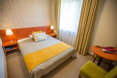 a bedroom with a bed and a table and a window at Žuvėdra in Ignalina