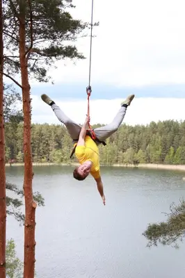 a man on a rope swing over a lake at Žuvėdra in Ignalina