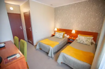 a hotel room with two beds and a desk at Žuvėdra in Ignalina