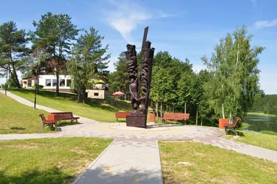 a statue in a park with benches and a lake at Žuvėdra in Ignalina