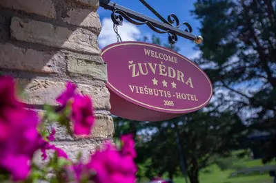 a sign hanging on a brick wall with pink flowers at Žuvėdra in Ignalina